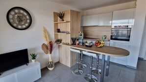 A modern kitchen with a wooden countertop, white cabinets, a built-in oven, and a wall-mounted clock.