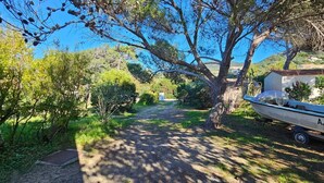 A narrow gravel path flanked by trees and shrubs, leading to a white boat with the registration number AJB35838. - T3 Paradise on the beach, feet in the water (Olmeto)