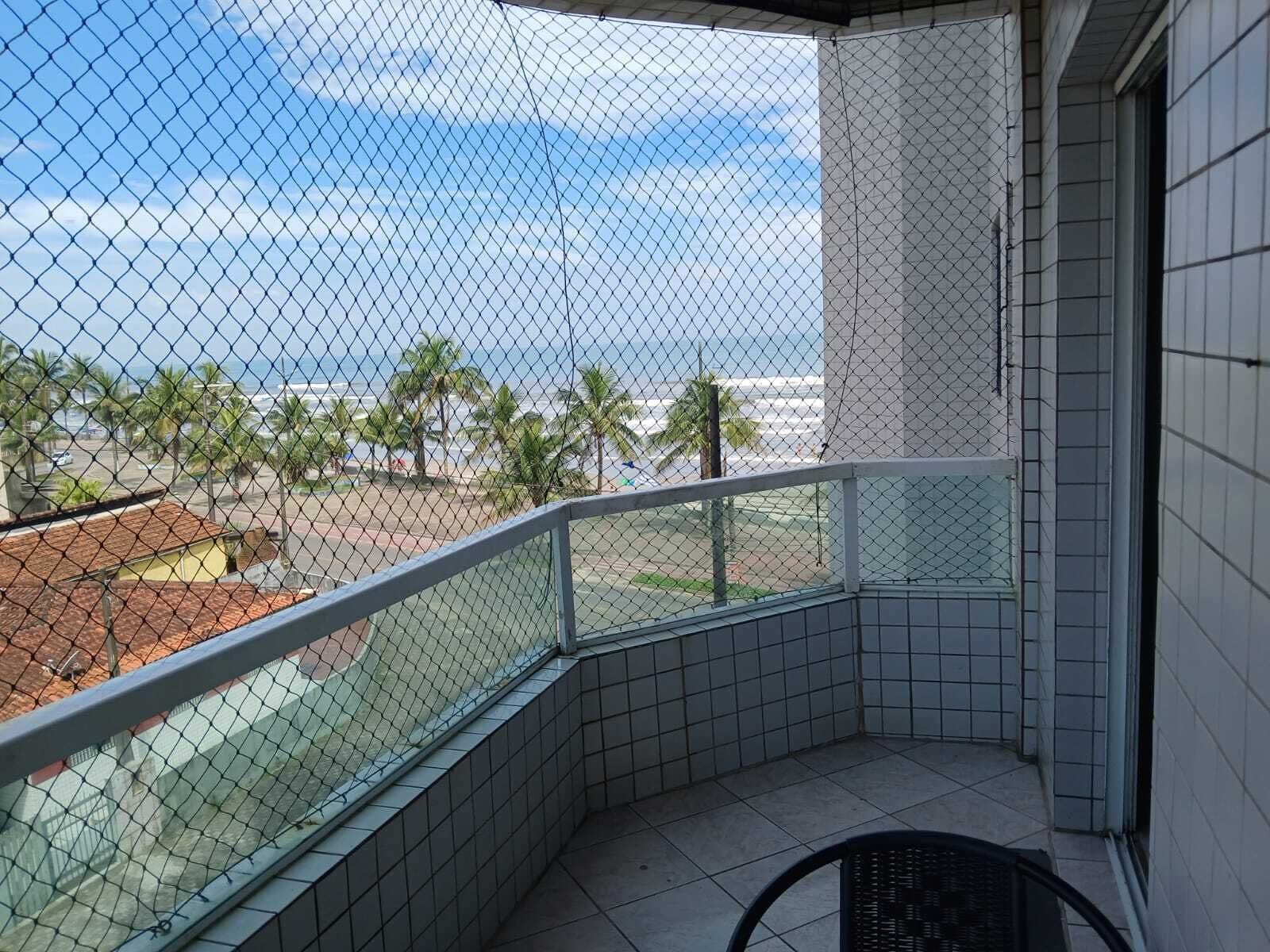 Uma varanda com vista para o oceano e palmeiras.