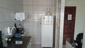 Una cocina compacta con encimera de granito, refrigerador blanco, cafetera y salpicadero de azulejos.