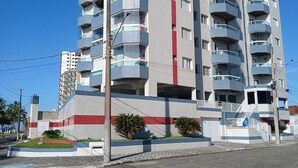 Un edificio residencial de varios pisos, con balcones, un garaje para estacionar y un acceso con puerta de reja.