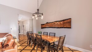 A dining area with a wooden table and chairs, a chandelier, and a large wooden art piece on the wall. - Mountain Views, Game Room, Firepit and Hot Tub in Bryson City (Bryson City)