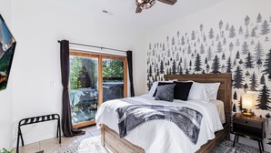 A bedroom with a bed, a nightstand, a ceiling fan, a window with curtains, and a wall mural. - Mountain Views, Game Room, Firepit and Hot Tub in Bryson City (Bryson City)