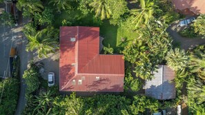 A red-roofed building surrounded by lush greenery and palm trees.