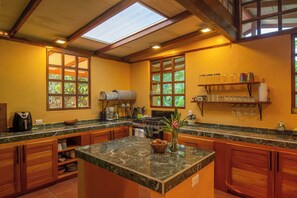 A kitchen with a central island, wooden cabinets, and a window overlooking greenery.