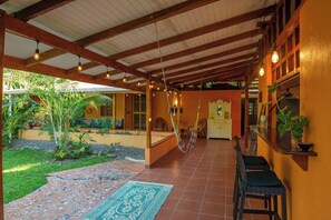 A covered outdoor area with a hammock, a tiled floor, and a patterned rug.