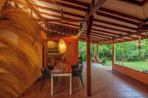 An indoor dining area with a wooden table, chairs, and a hanging light fixture.