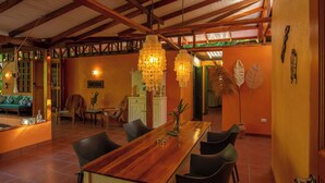 Un comedor amplio con una mesa y sillas de madera, un lámpara colgante y vista a otra habitación.