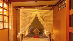 Una cama con dosel, un almohadón y un objeto rojo sobre la cama.