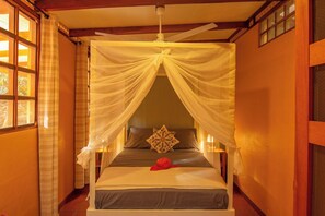 A bed with a canopy, a pillow, and a red object on the bed.
