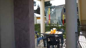 An outdoor seating area with a table and chairs, a netted structure in the background, and a clear view of the surrounding area. - Holiday apartment with air conditioning and garden (Bibione)