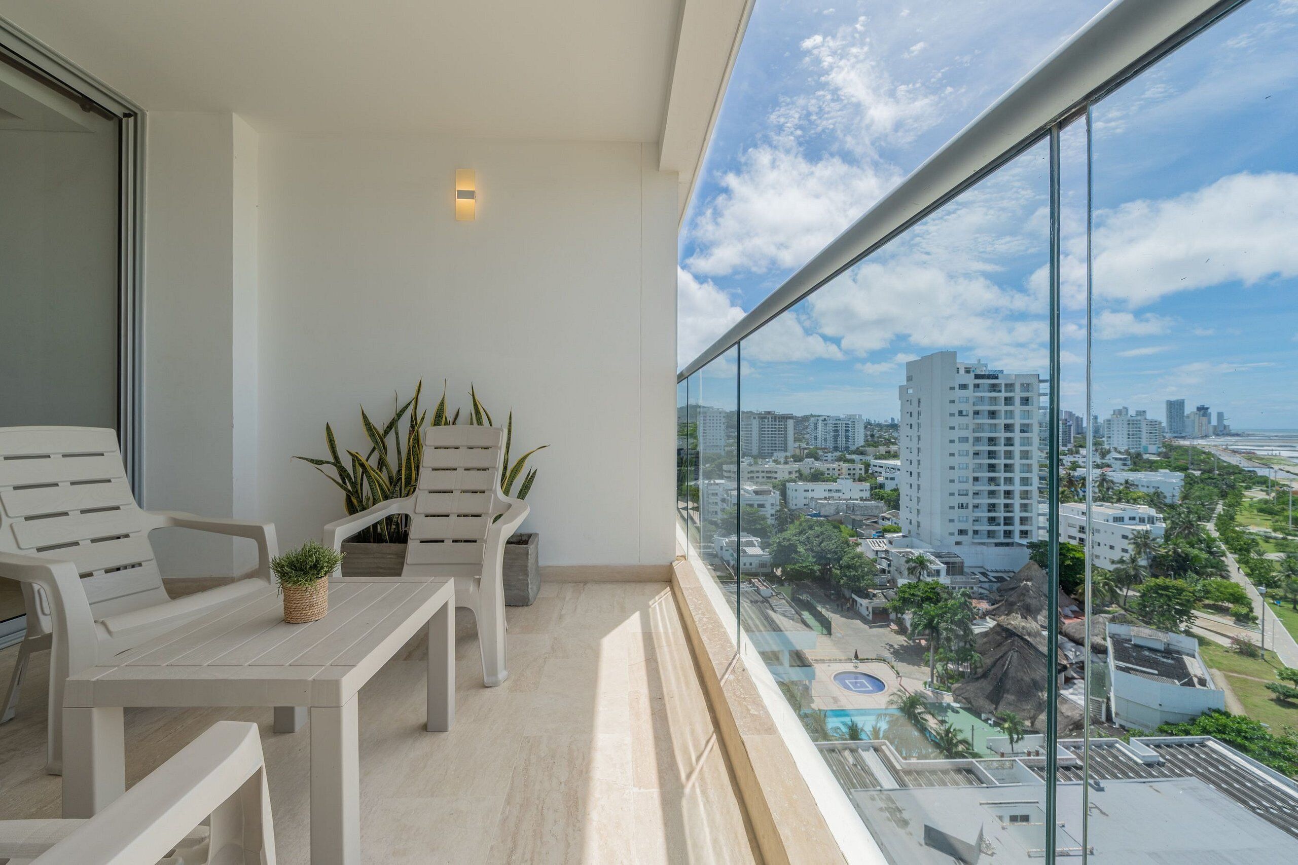 A balcony with a view of a cityscape, including high-rise buildings and a swimming pool.