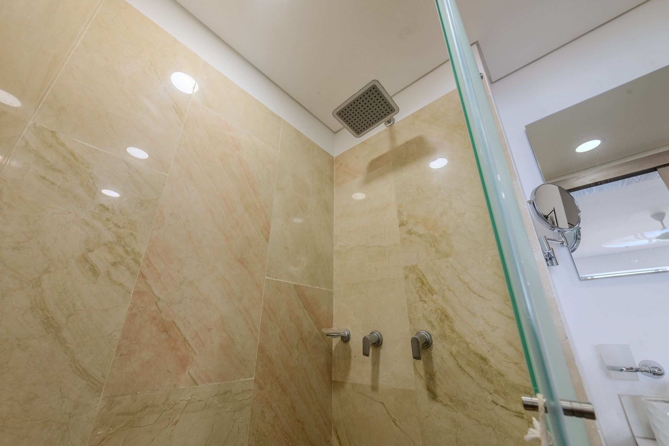 A modern bathroom with marble walls, a glass shower enclosure, and a visible sink area.