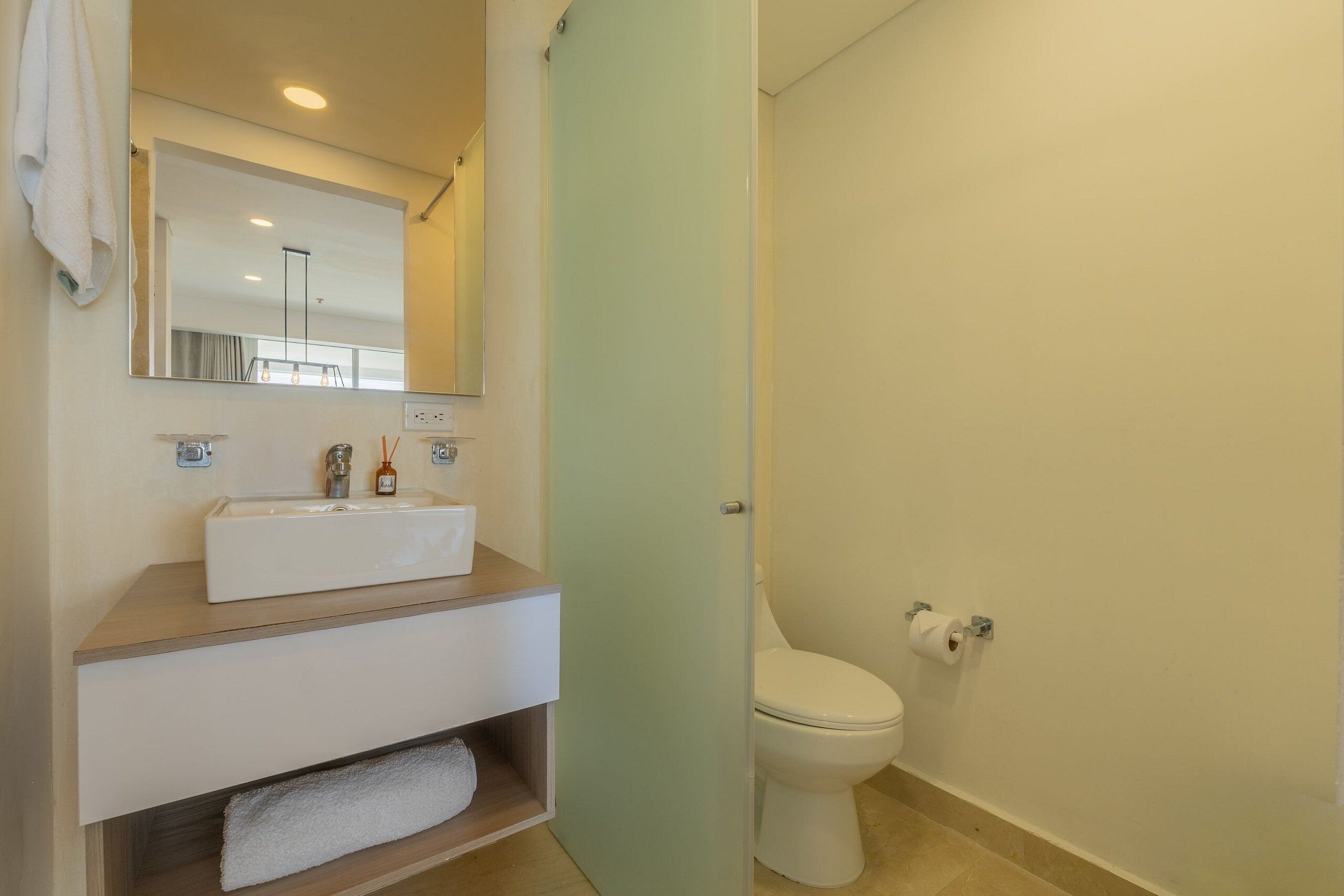 A bathroom with a white sink, mirror, and toilet.