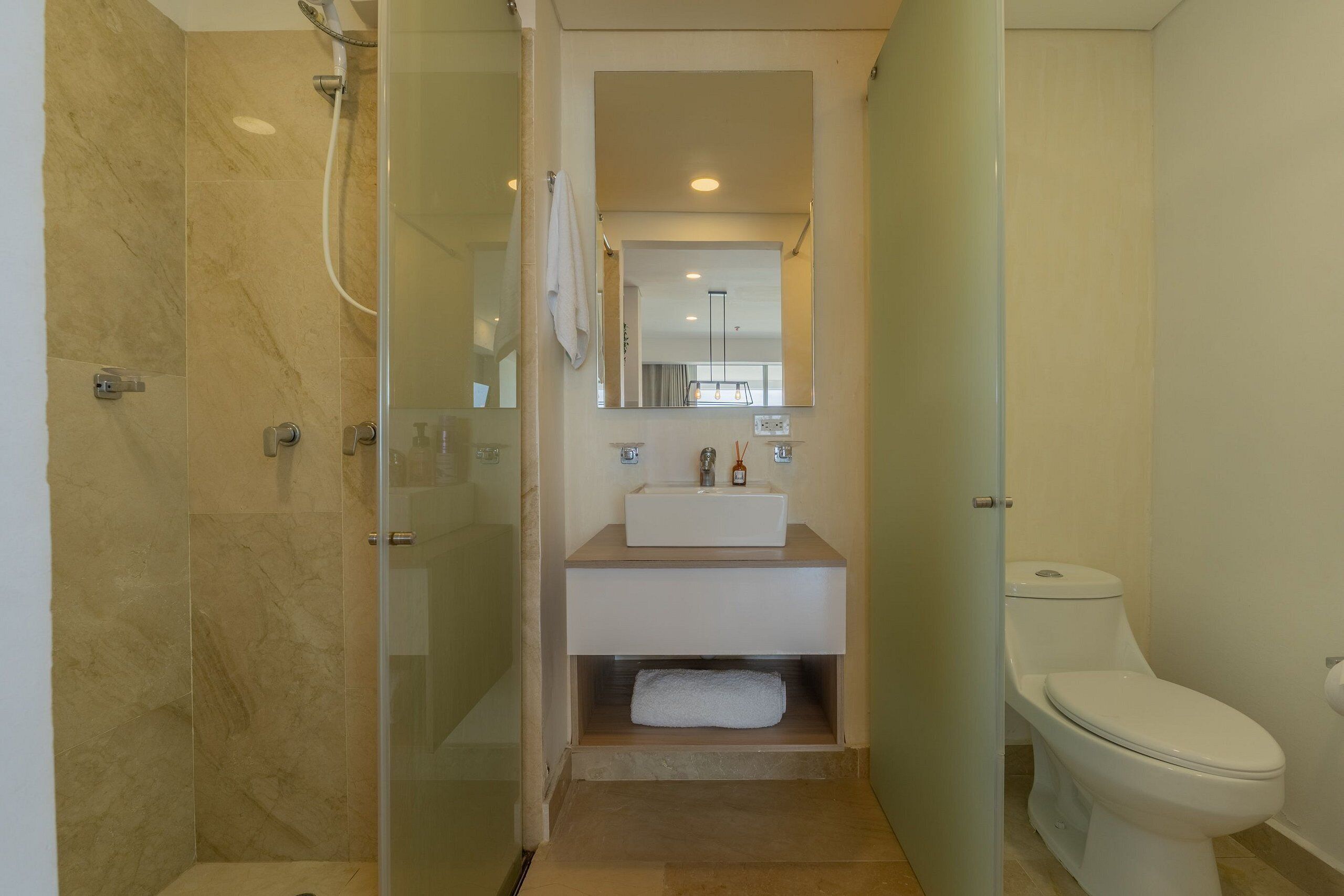 A modern bathroom with a glass-enclosed shower, a white sink, and a toilet.