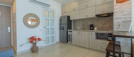 Una cocina moderna con armarios de madera clara, un refrigerador de acero inoxidable y una cafetera.