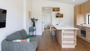 A modern kitchen with a central island, wooden cabinets, and a built-in oven.