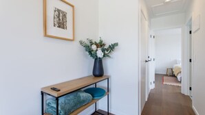 A hallway with a wooden console table, a vase with flowers, and a framed picture on the wall.