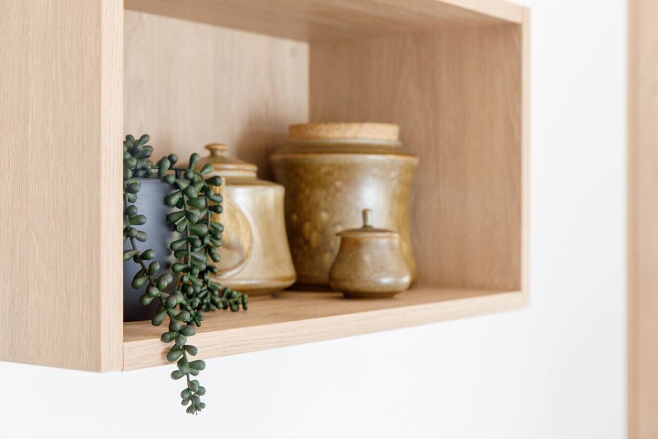 A wooden shelf with ceramic containers and a small plant.