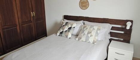 Ein Schlafzimmer mit Bett, Kleiderschrank, Nachttisch und einer Pendelleuchte.
