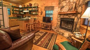 Ein gemütliches Cabin-Interieur mit Kamin aus Stein, Holzmöbeln und einem Fernseher im Wohnbereich.