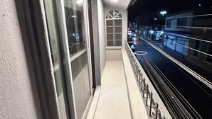 Un balcon donnant sur une rue la nuit.