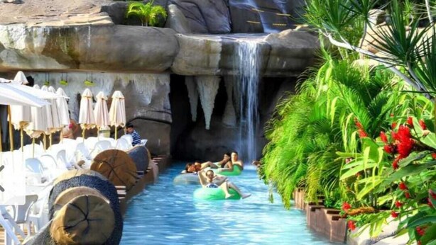 A water slide with people on tubes, surrounded by lounge chairs and umbrellas. - Spazzio diRoma Charme II with free entrance to Acqua Park, Splash Caldas Novas (Caldas Novas)