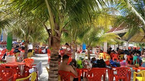 An outdoor seating area with red plastic chairs and tables, shaded by palm trees. - Spazzio diRoma Charme II with free entrance to Acqua Park, Splash Caldas Novas (Caldas Novas)