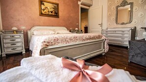 Une chambre à coucher comprenant un lit, une table de chevet, une commode, un miroir et une porte donnant sur une autre pièce.