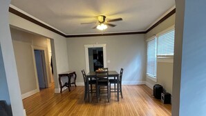 A spacious living room with hardwood flooring, a dining area with a table and chairs, a ceiling fan, and a large window with blinds. - Magic City Home walkable to Top Golf, New Amphitheater, Uptown, City Walk &more! (Birmingham)