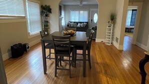 A dining area with a wooden table and chairs, a ceiling fan, and a view into the kitchen. - Magic City Home walkable to Top Golf, New Amphitheater, Uptown, City Walk &more! (Birmingham)