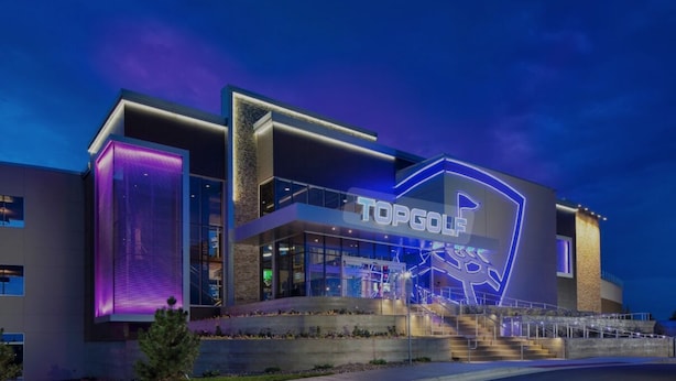 A modern building with a prominent 'TopGolf' sign, large glass windows, and a well-lit entrance. - Magic City Home walkable to Top Golf, New Amphitheater, Uptown, City Walk &more! (Birmingham)
