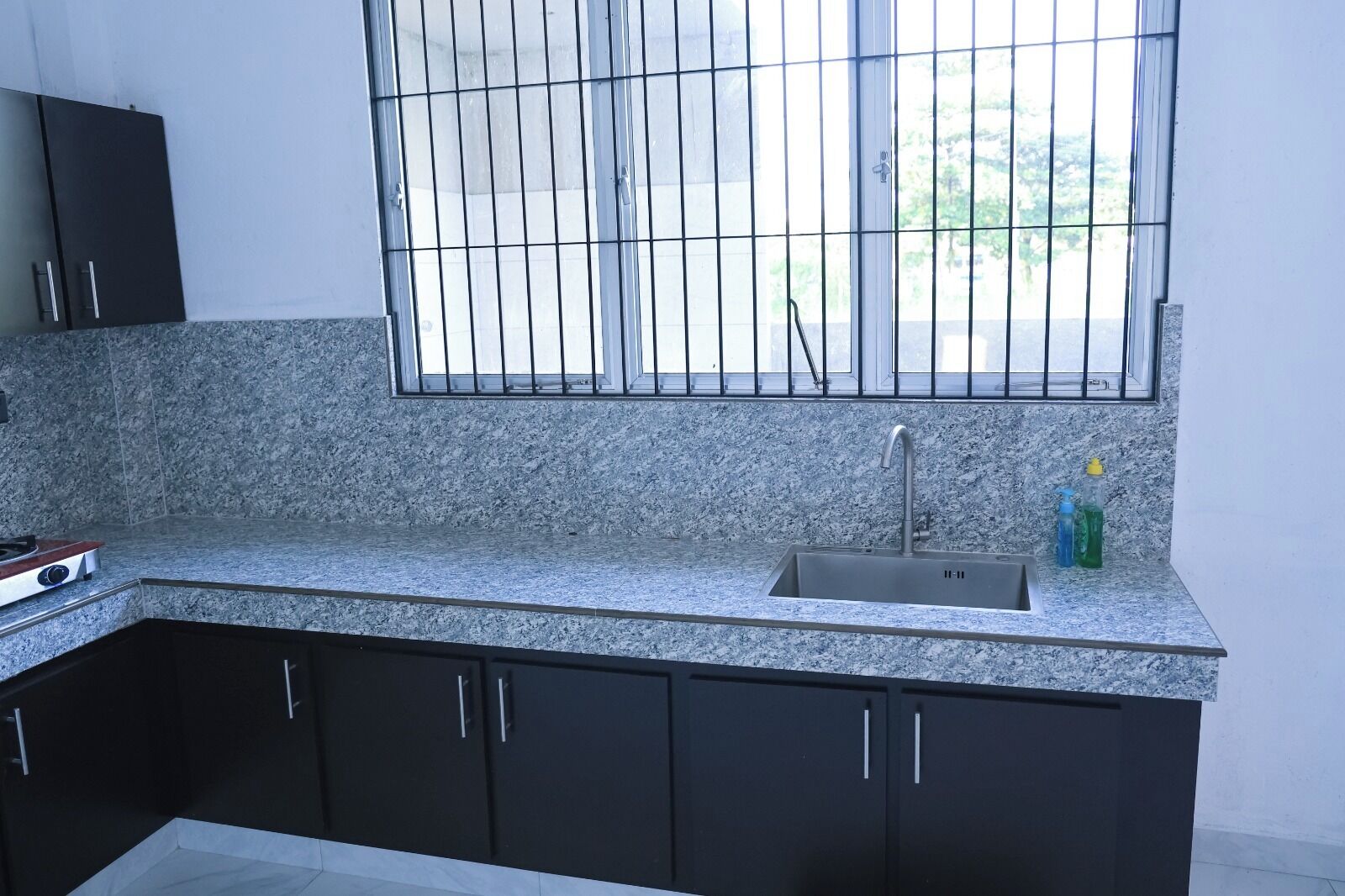 A kitchen with granite countertops, a stainless steel sink, and black cabinets.
