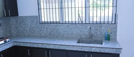 A kitchen with granite countertops, a stainless steel sink, and black cabinets.
