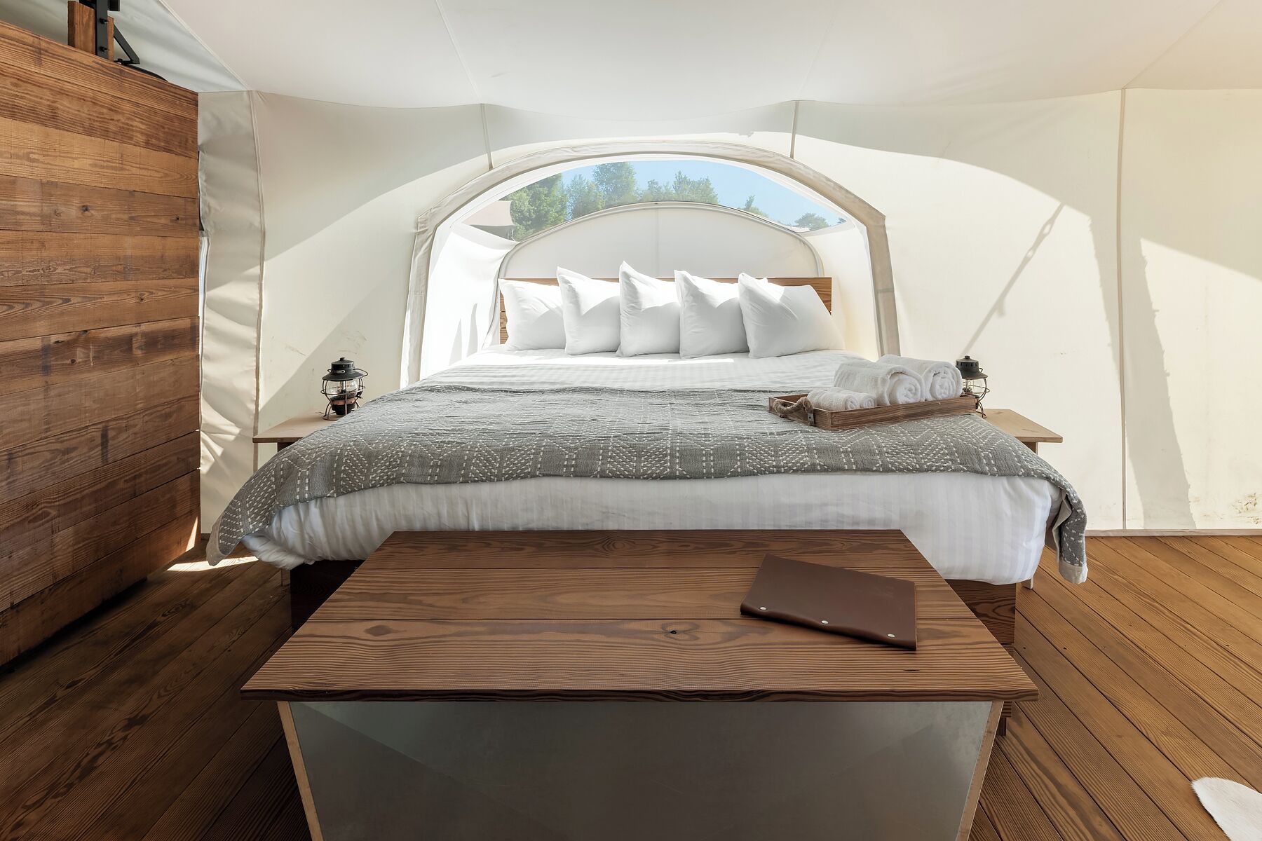 A tented room with a bed, a table, and a lantern.