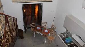 A dining area with a wooden table, four chairs, a map on the wall, a kitchen with a sink and cabinets, and a staircase. - First-floor housing located within the city's Ancient Walls. (Castellammare del Golfo (TP))