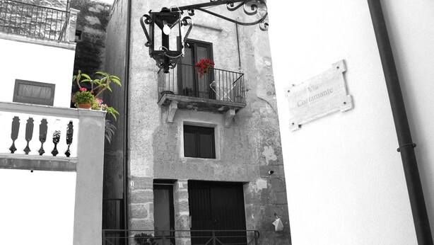 A narrow street with a building featuring a balcony with a flower pot and a sign reading "Via Costamante". - First-floor housing located within the city's Ancient Walls. (Castellammare del Golfo (TP))