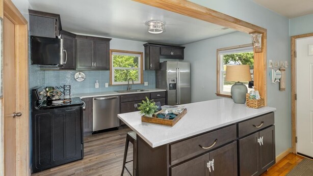 A modern kitchen with dark cabinets, stainless steel appliances, and a central island. - Beach Glass block from Heart of Saugatuck! (Saugatuck)