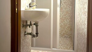 Un baño con lavamanos, ducha y paredes con azulejos.