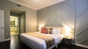 Ein Schlafzimmer mit einem großen Bett, einem Nachttisch und einer Lampe. Eine Tür führt zu einem Badezimmer.