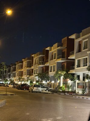 A row of modern multi-story residential buildings at night with street lighting. - The Privacy Villa (6th of October City)