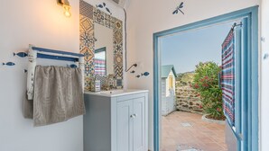 Een badkamer met een betegelde muur, een spiegel, een handdoekhouder en een kast.