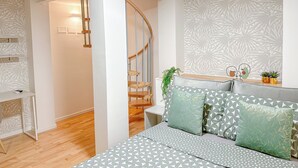 A modern bedroom with a wooden staircase, a patterned wall, and a bed with geometric pillows. - Brunacci Suite - 5 min dai Navigli (Milano)