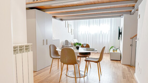A modern dining area with a wooden table, four chairs, and a white ceiling. - Brunacci Suite - 5 min dai Navigli (Milano)