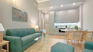 A modern living room with a green sofa, a glass coffee table, and wicker chairs. - Cirillo Luxury Suite 16 - Arco della Pace (Milano)