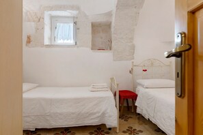 A small, cozy bedroom with two single beds, a window, and a door.