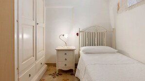 Un dormitorio con una cama, una mesita de noche con lámpara, un armario y un radiador.
