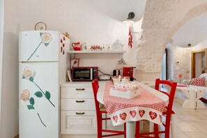 Eine Küche mit Kühlschrank, Mikrowelle und Esstisch, gedeckt für das Essen.