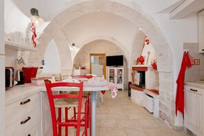 A kitchen with white cabinets, a red chair, and a TV mounted on the wall.