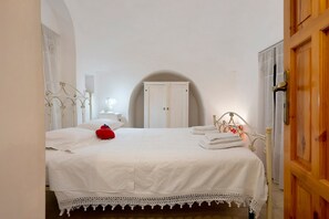 A bedroom with a bed, a nightstand, a lamp, a wardrobe, and a door with a wooden frame. - Trullo 'Vito with Pool' with Private Pool, Shared Terrace and Wi-Fi (Martina Franca)